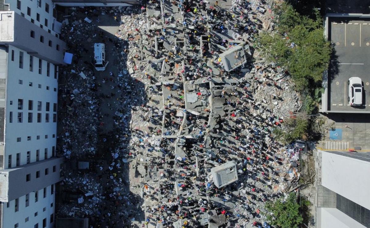 Residentes y equipos de rescate buscan entre los escombros tras un terremoto.