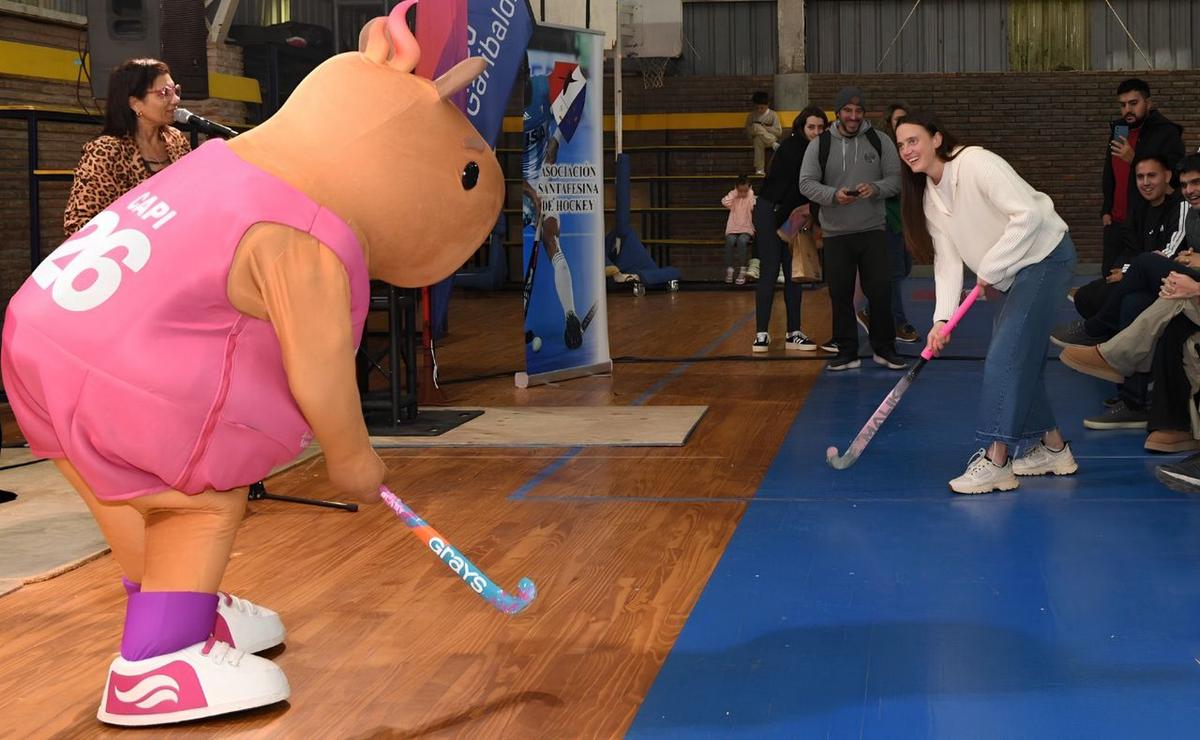Capi, la mascota oficial de los Suramericanos Santa Fe 2026 jugando al hockey.