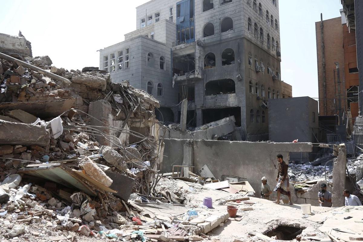 Personas inspeccionando los edificios dañados por los ataques aéreos saudíes, en Saná, Yemen.