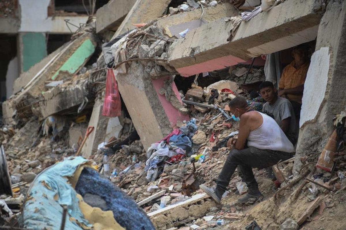 Personas sentadas sobre los escombros de un edificio colapsado en Caraballeda, estado La Guaira.