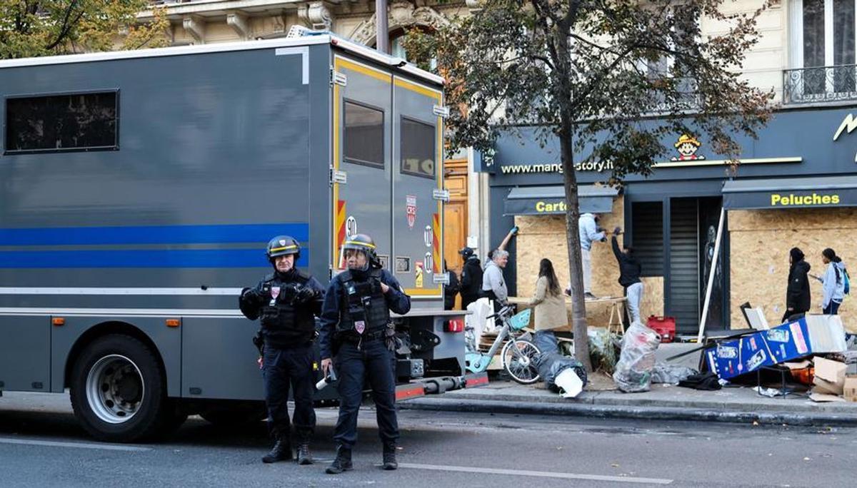 Fuerzas de seguridad vigilan frente a una tienda.