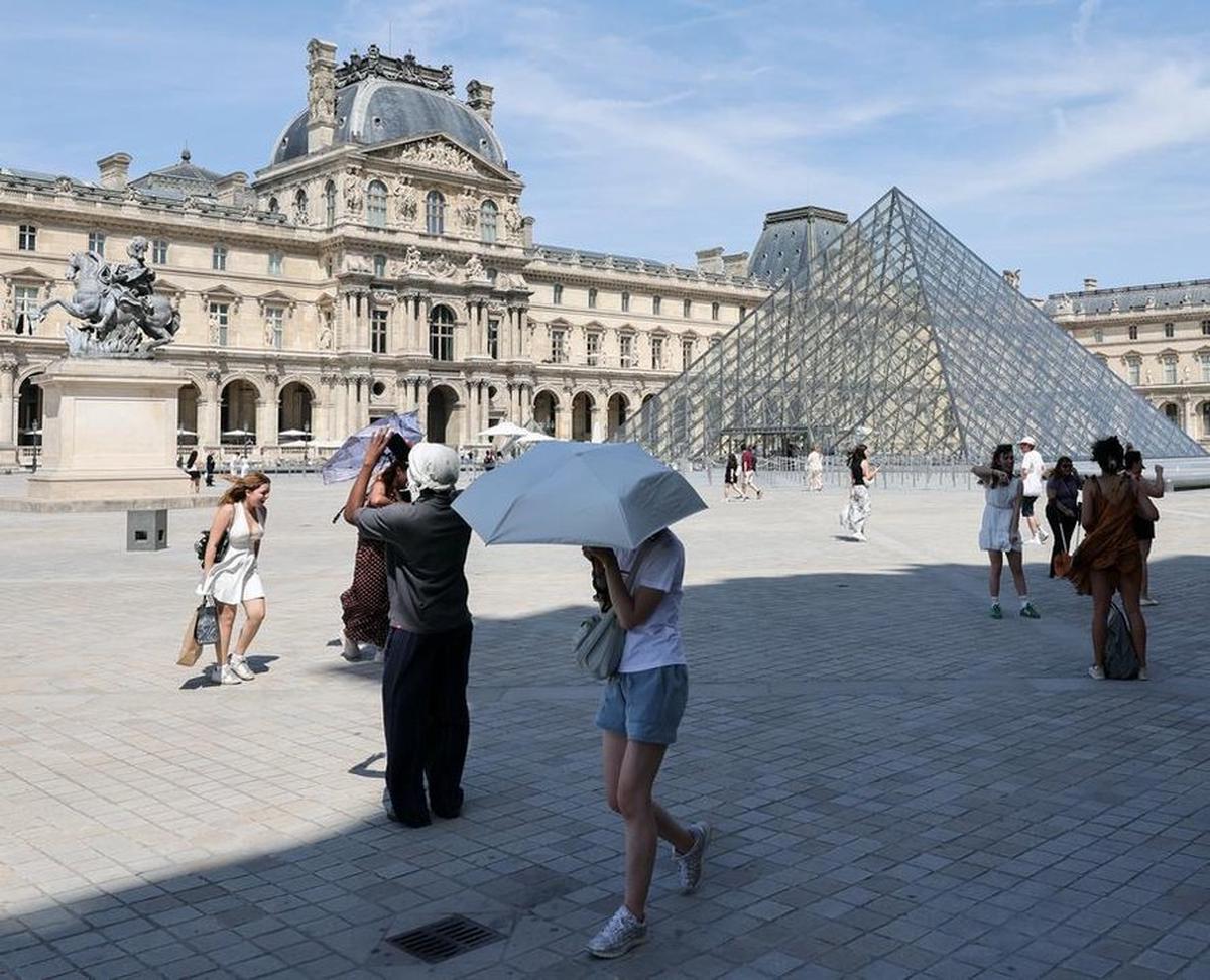 Visitantes caminan frente al Museo de Louvre en medio de una ola de calor, en París, Francia.