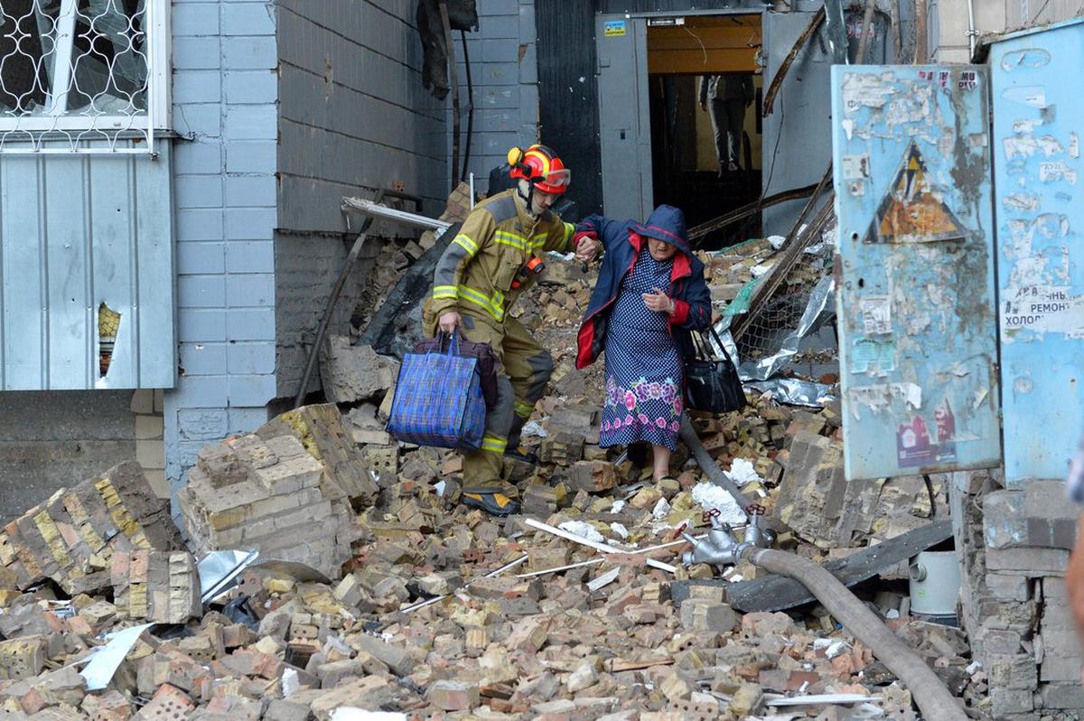 Imagen del 20 de agosto de 2026 de un rescatista ayudando a una mujer a evacuar un edificio dañado en un ataque nocturno ruso con misiles y drones, en Kiev, Ucrania.
