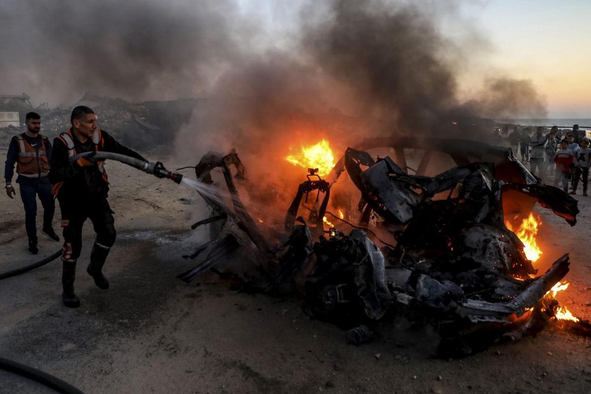 Imagen de archivo de rescatistas mientras apagan un auto tras un ataque aéreo.