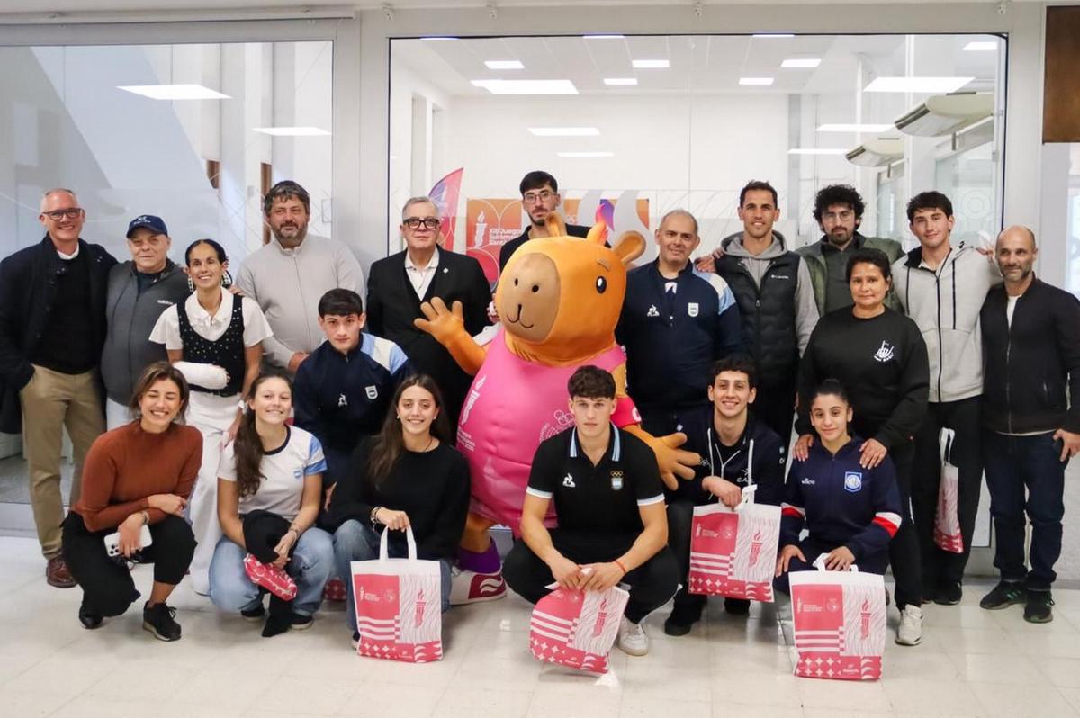 Los deportistas posan con Capi 26, la mascota de los juegos.